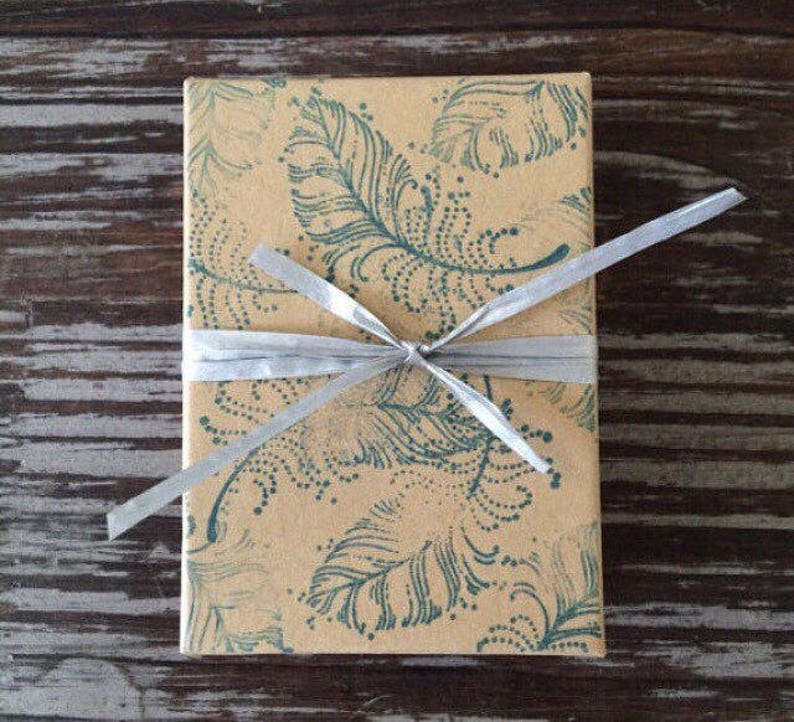 May include: A brown gift box with a blue and white feather pattern is wrapped with a silver ribbon.