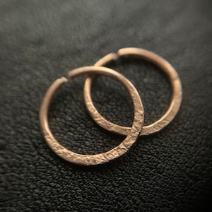 May include: Two gold hoop earrings with a textured surface.