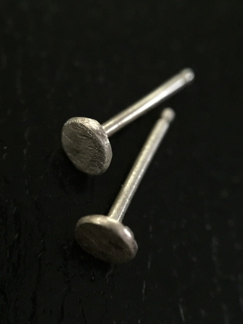 May include: A pair of silver stud earrings with a round, textured design.