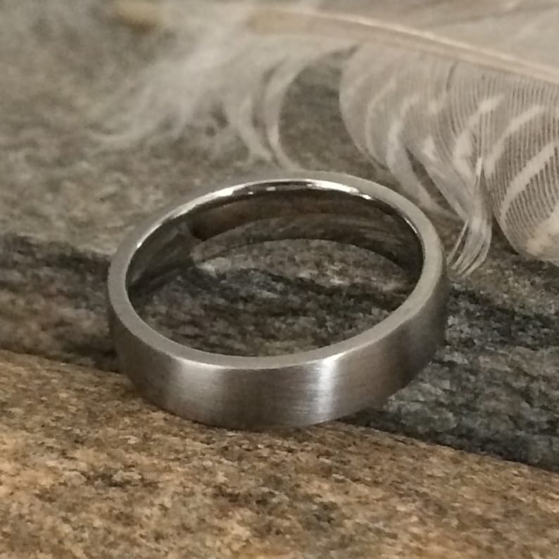 Op de afbeelding: Een zilveren ring met een geborstelde afwerking. De ring is simpel en elegant.