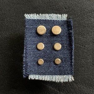 May include: Six silver-toned round stud earrings on a blue fabric background.
