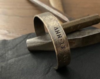 Puede incluir: Un brazalete de cobre con la inscripción "IX - MMV" en la parte delantera.