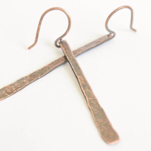 May include: A pair of long, hammered copper earrings with a simple wire hook closure.