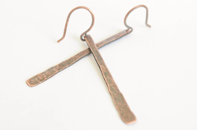 May include: A pair of long, hammered copper earrings with a simple wire hook closure.