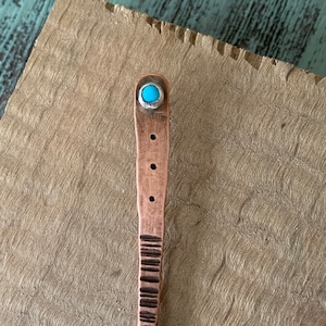 May include: A copper hair stick with a turquoise stone accent. The stick has a textured design and is approximately 25 cm long.