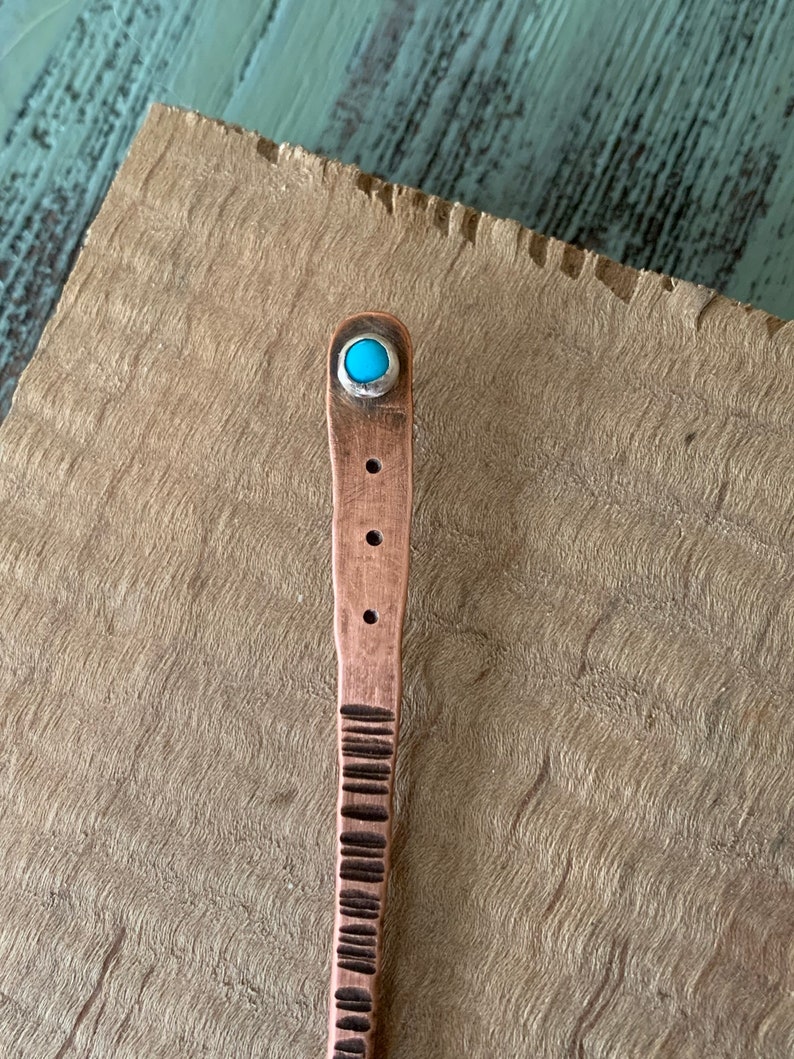 May include: A copper hair stick with a turquoise stone accent. The stick has a textured design and is approximately 25 cm long.