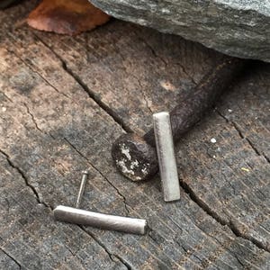 May include: A pair of silver bar stud earrings. The earrings are simple and minimalist, and they are perfect for everyday wear.