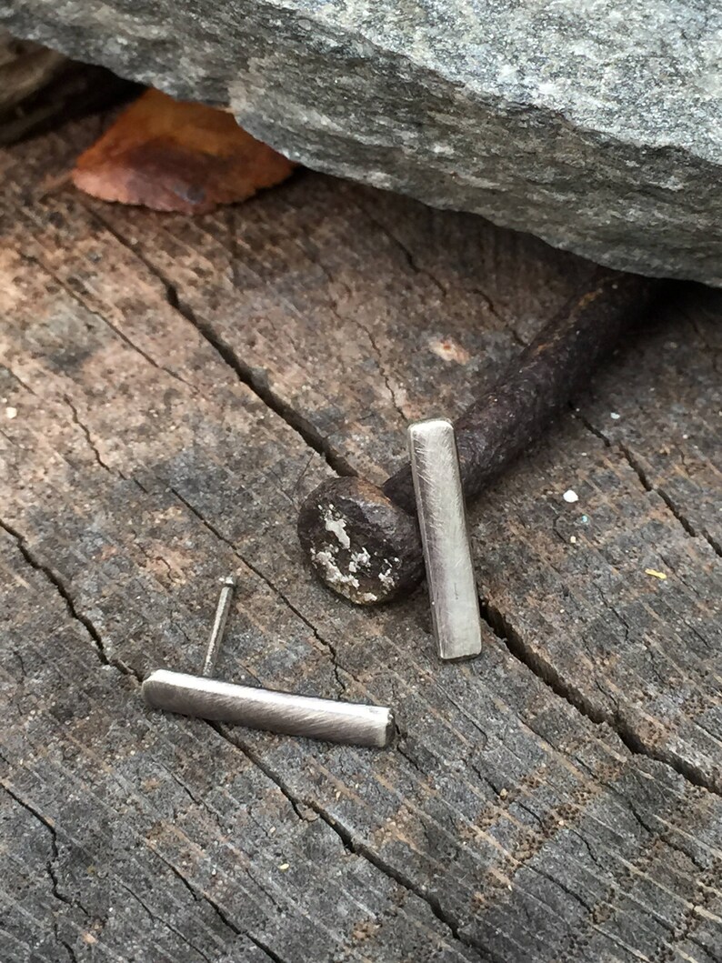 May include: A pair of silver bar stud earrings. The earrings are simple and minimalist, and they are perfect for everyday wear.