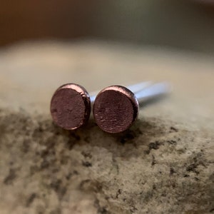 May include: A pair of small, round, rose gold stud earrings.