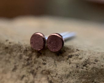May include: A pair of small, round, rose gold stud earrings.