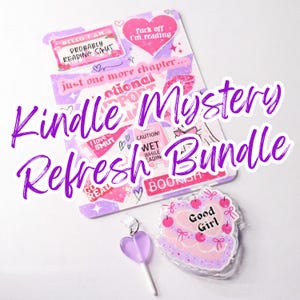 May include: A Kindle Mystery Refresh Bundle with stickers and a lollipop. The stickers have phrases like "Hello I am probably reading smut" and "fuck off I'm reading". The bundle includes a cake-shaped item with "Good Girl" on it.