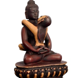 Puede incluir: Estatua de Buda de madera en posición de meditación sentado, con una figura abrazando al Buda. La estatua es principalmente marrón oscuro con acentos beige claro. La base presenta un diseño detallado de flor de loto.