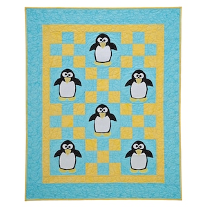 Op de afbeelding: Een gewatteerde deken met een herhalend pinguïnpatroon. De quilt heeft een lichtblauwe achtergrond met een geel en blauw dambordpatroon in het midden. De pinguïns zijn zwart en wit met gele voeten.