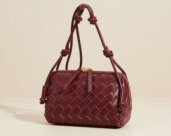 Bolso bandolera de piel auténtica tejida color burdeos, con correa de nudo trenzado.