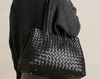 Bolso tote de piel tejida negra con asas trenzadas.