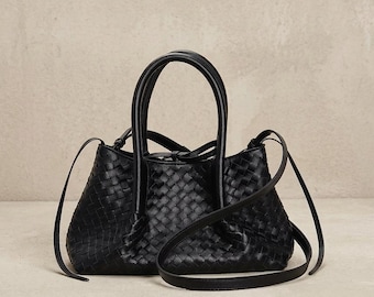Bolso de mano negro de piel trenzada con asas superiores y correa para llevarlo cruzado.