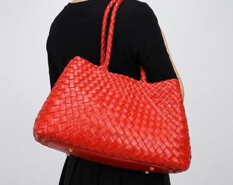 Bolso tote de piel tejida roja con asas trenzadas.