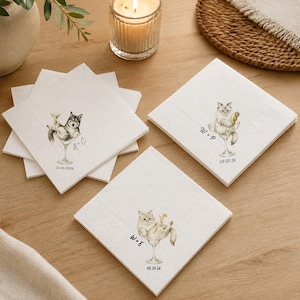 May include: A set of square white paper napkins featuring illustrations of cats sitting in cocktail glasses. Each napkin displays a unique pair of initials and a date, including A+C 12-09-2026, W+P 08.20.26, and W+E 08.20.26, printed in black ink.