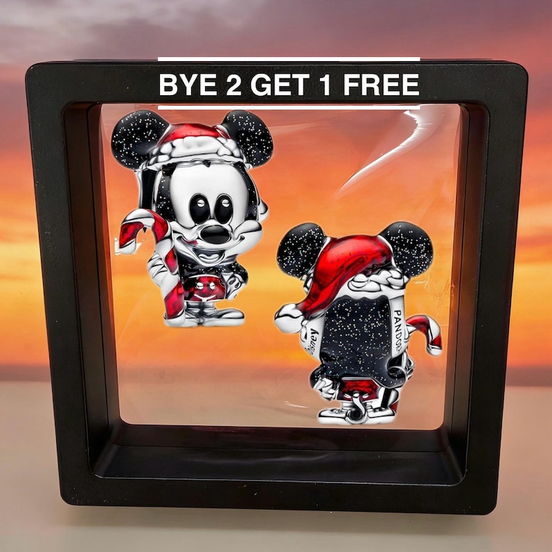 May include: Two Mickey Mouse charms in a black display case. Each charm is silver with black ears, a red Santa hat, and a candy cane. The text "BYE 2 GET 1 FREE" is above the charms.