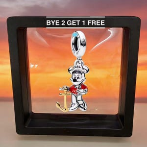 Puede incluir: Un charm de plata con un personaje de dibujos animados con un atuendo de marinero, sosteniendo un ancla dorada. El charm cuelga de un anillo plateado. El texto "BYE 2 GET 1 FREE" est&aacute; en la parte superior de la imagen.