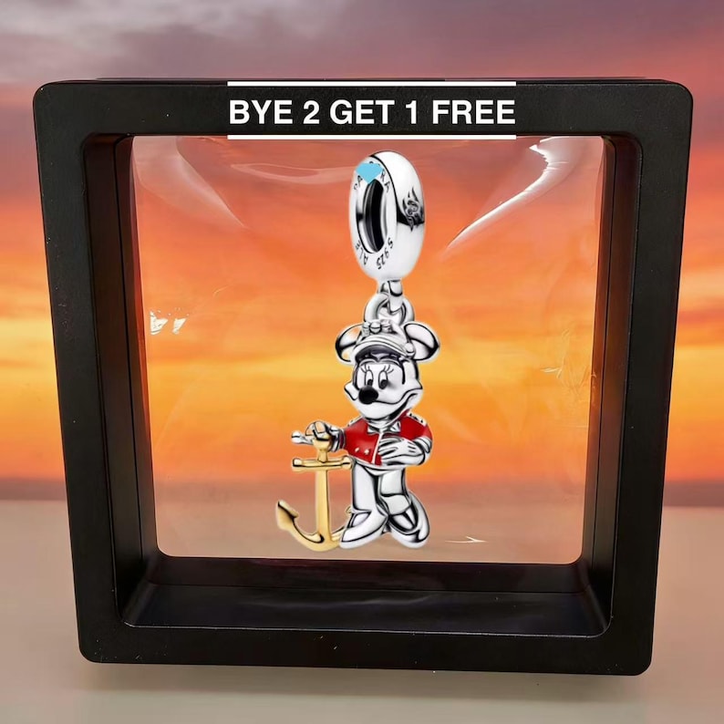 Puede incluir: Un charm de plata con un personaje de dibujos animados con un atuendo de marinero, sosteniendo un ancla dorada. El charm cuelga de un anillo plateado. El texto "BYE 2 GET 1 FREE" est&aacute; en la parte superior de la imagen.