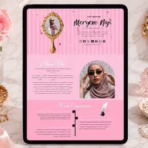 Può includere: Un tablet digitale mostra un curriculum rosa e bianco con il testo "UGC Creator Meryem Naji". Il curriculum include una foto, uno specchio con cornice dorata e una sezione intitolata "About Me". Una candela accesa e rose rosa sono sullo sfondo.