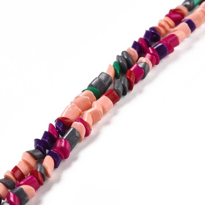 May include: A multi-colored beaded necklace with pink, red, purple, green, and gray beads. The beads are all different shapes and sizes.