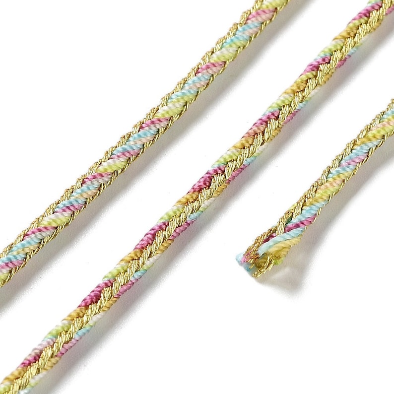May include: Close-up of decorative trim with a braided design. The trim features a gold metallic edge with a pastel-colored braided center in shades of pink, yellow, and blue. The trim is ideal for sewing and craft projects.
