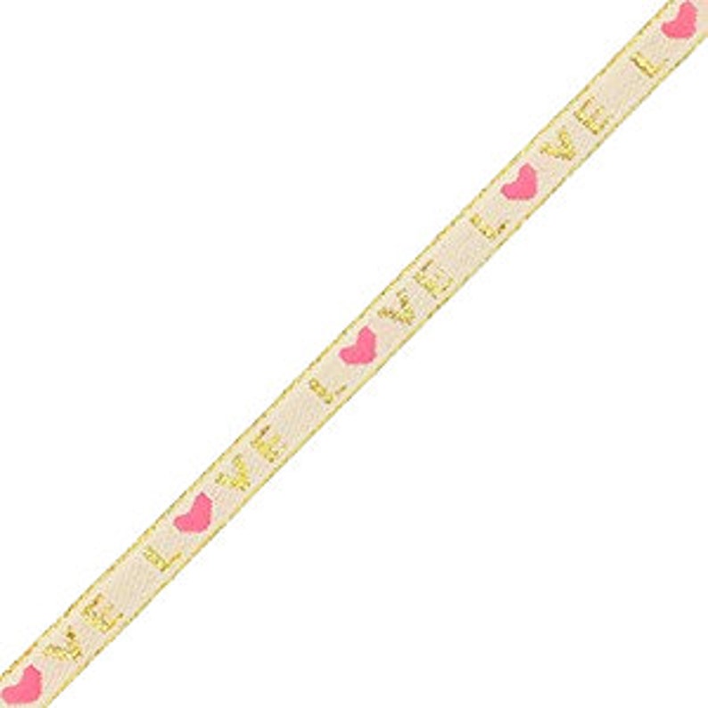 May include: A cream-colored ribbon with gold text that reads "LOVE" and pink heart shapes. The ribbon has a gold border and is angled diagonally across the frame. The ribbon is likely used for crafting, gift wrapping, or decorative purposes.