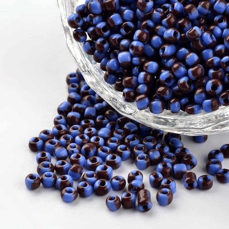 May include: A bowl of blue and brown glass seed beads. The beads are small and round, and they are arranged in a random pattern.