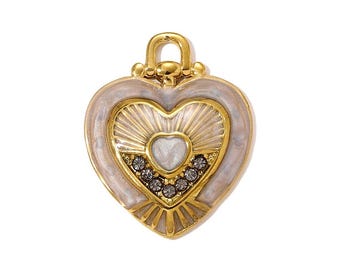 May include: A gold heart pendant with a white enamel border. The pendant has a sunburst design and is decorated with small, dark grey crystals. A small loop is at the top for attaching to a chain.