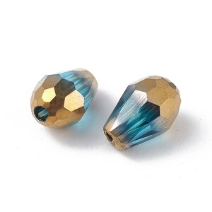 May include: Two teardrop-shaped glass beads with a gold and blue iridescent finish. The beads have a faceted design and a hole for stringing.