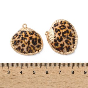 May include: Two gold-toned shell charms with a leopard print design. The charms are approximately 2.5 inches in length.