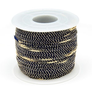 May include: A spool of navy blue and gold cord. The cord is wound around a white plastic spool.