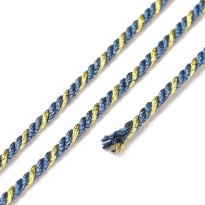Pode incluir: Um close-up de um cordão torcido azul e dourado. O cordão é feito de duas meadas de fio, uma azul e uma dourada, que são torcidas juntas.