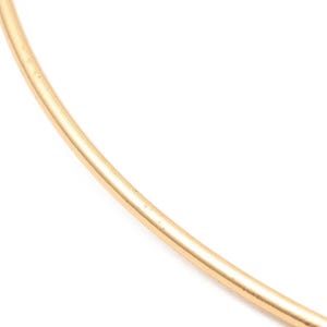 May include: A simple gold bangle bracelet. The bracelet is made of a single, thin band of gold.