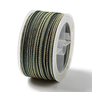 May include: A spool of green and gold striped cord. The cord is wound around a clear plastic spool with a label.