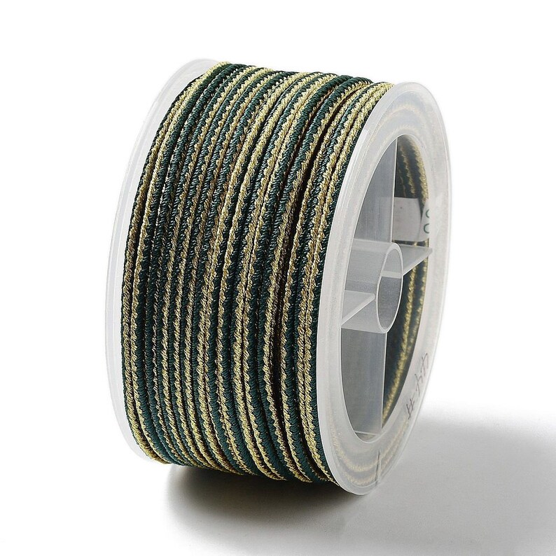 May include: A spool of green and gold striped cord. The cord is wound around a clear plastic spool with a label.