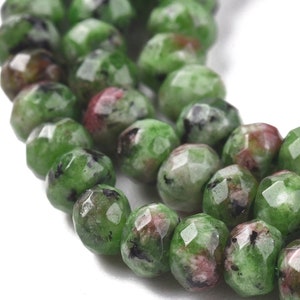 May include: A strand of green, pink, and black gemstone beads. The beads are faceted and have a rounded shape.