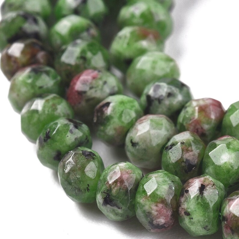 May include: A strand of green, pink, and black gemstone beads. The beads are faceted and have a rounded shape.