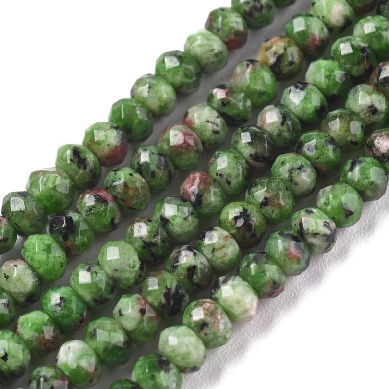 May include: A strand of green, black, and red gemstone beads. The beads are faceted and have a slightly irregular shape.