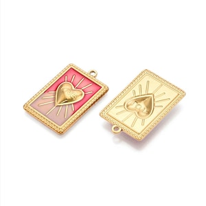 Peut inclure: Deux breloques en métal doré avec un motif en forme de cœur. Les breloques sont rectangulaires et présentent un cœur en relief avec le mot "love" inscrit à l'intérieur. L'une des breloques a un fond en émail rose et l'autre un fond en émail doré.