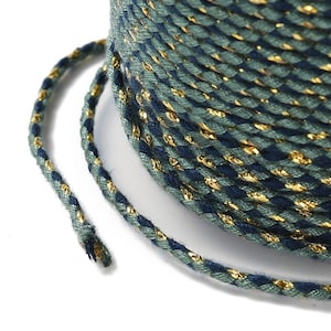 May include: A spool of blue and green twine with gold metallic thread woven throughout. The twine is coiled and a length of twine is extended from the spool.