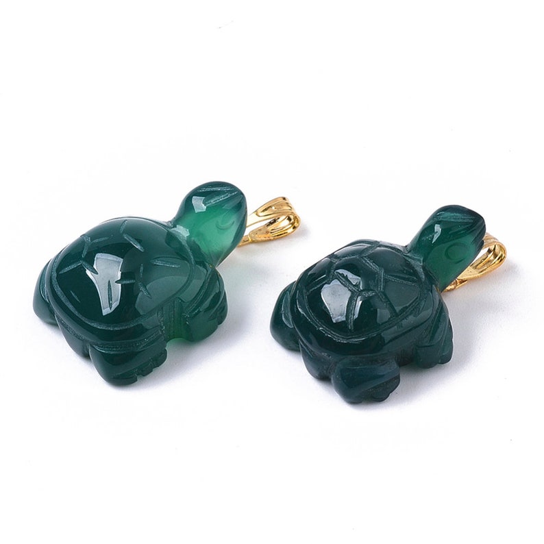 May include: Two green jade turtle pendants with gold-tone bail. The turtles are carved in detail and have a smooth, polished finish.