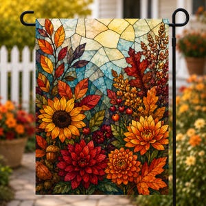 May include: A rectangular garden flag featuring a stained glass style illustration of autumn foliage, including sunflowers, dahlias, and acorns in shades of orange, red, and yellow against a light blue and white geometric background pattern.