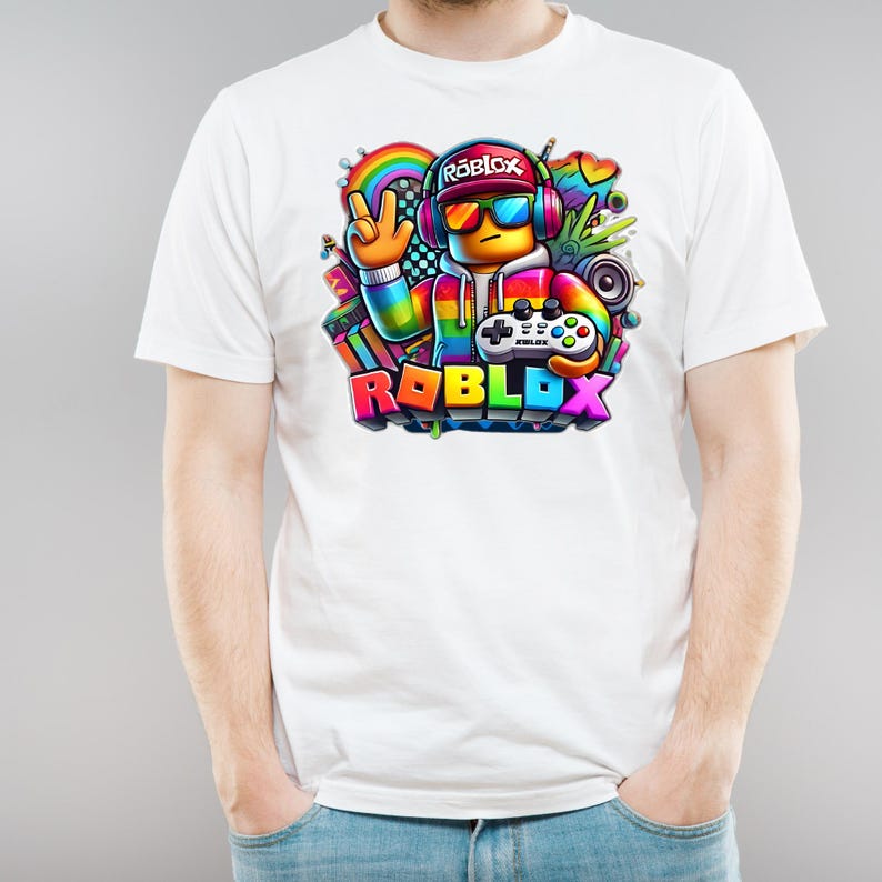 May include: White t-shirt with a vibrant Roblox graphic. The design showcases a character wearing headphones and sunglasses, holding a controller, and the Roblox logo. The graphic incorporates rainbow colours. A casual wear item.