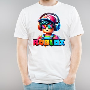 May include: White t-shirt with a vibrant Roblox character graphic. The character wears headphones and sunglasses, with the Roblox logo in rainbow colours below.