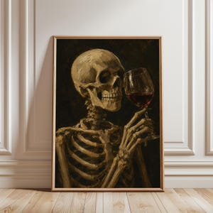 May include: A framed oil painting depicting a human skeleton in shades of beige and brown against a dark background. The skeleton is holding a clear glass filled with deep red liquid, positioned near its jawline, rendered in a painterly style.