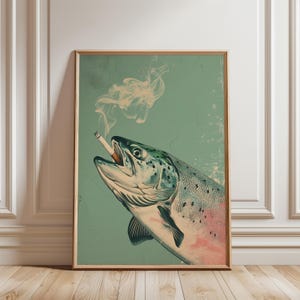 Könnte beinhalten: Gerahmter Kunstdruck mit einer Illustration eines Fisches, der eine Zigarette raucht. Die Illustration verwendet Grün- und Rosatöne vor einem türkisfarbenen Hintergrund. Rauch steigt von der Zigarette auf und erzeugt ein skurriles Bild. Der Druck ist in einem Holzrahmen.