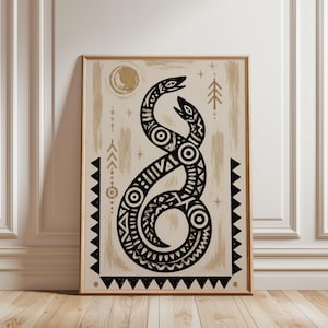 May include: A rectangular wall art print in a light wood frame featuring a black ink illustration of two intertwined snakes with geometric patterns. The design includes a gold moon, stars, and arrow symbols on a cream background with gold brushstrokes.